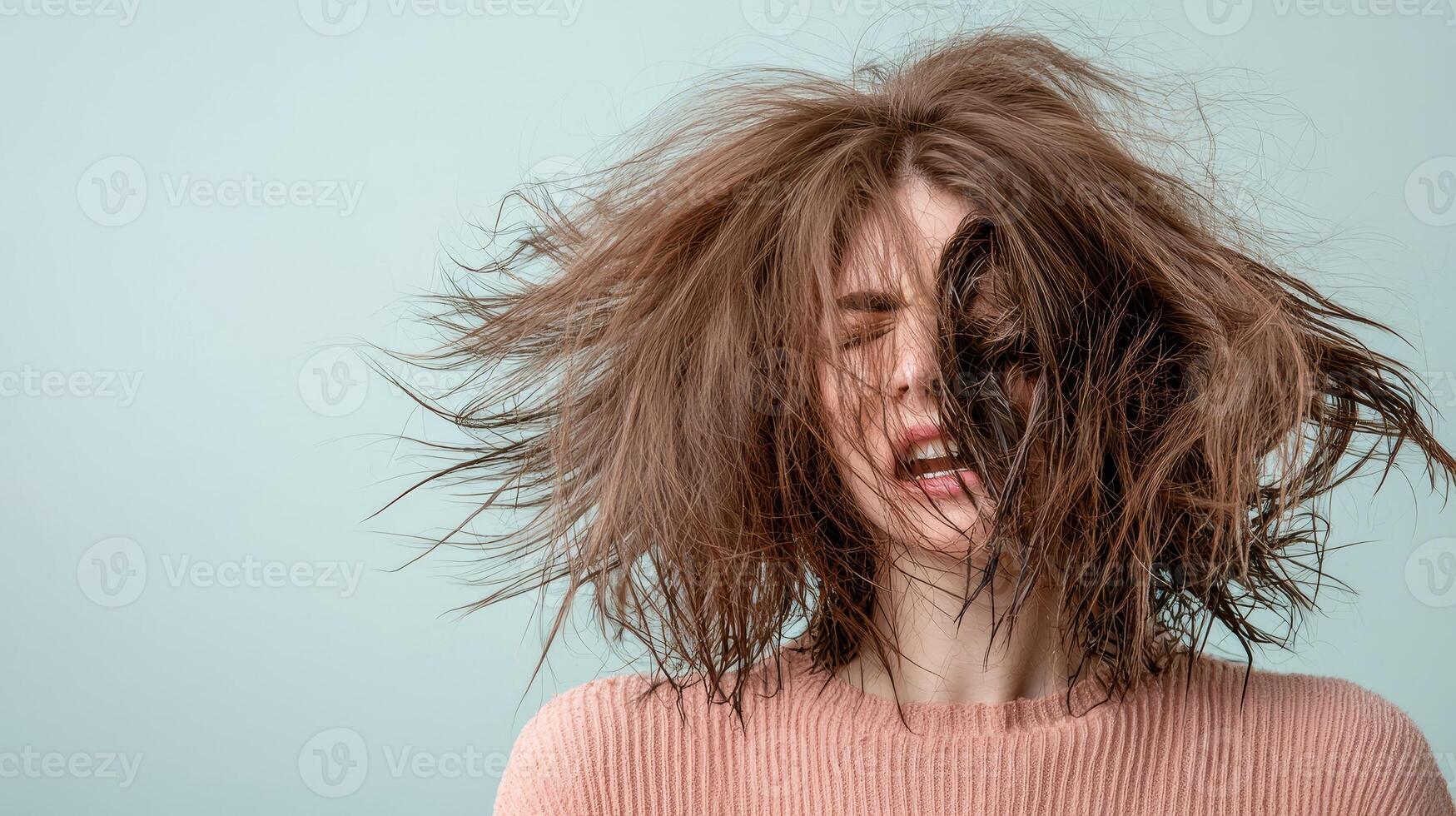 Woman with messy hair expressing emotions against a blue background. photo
