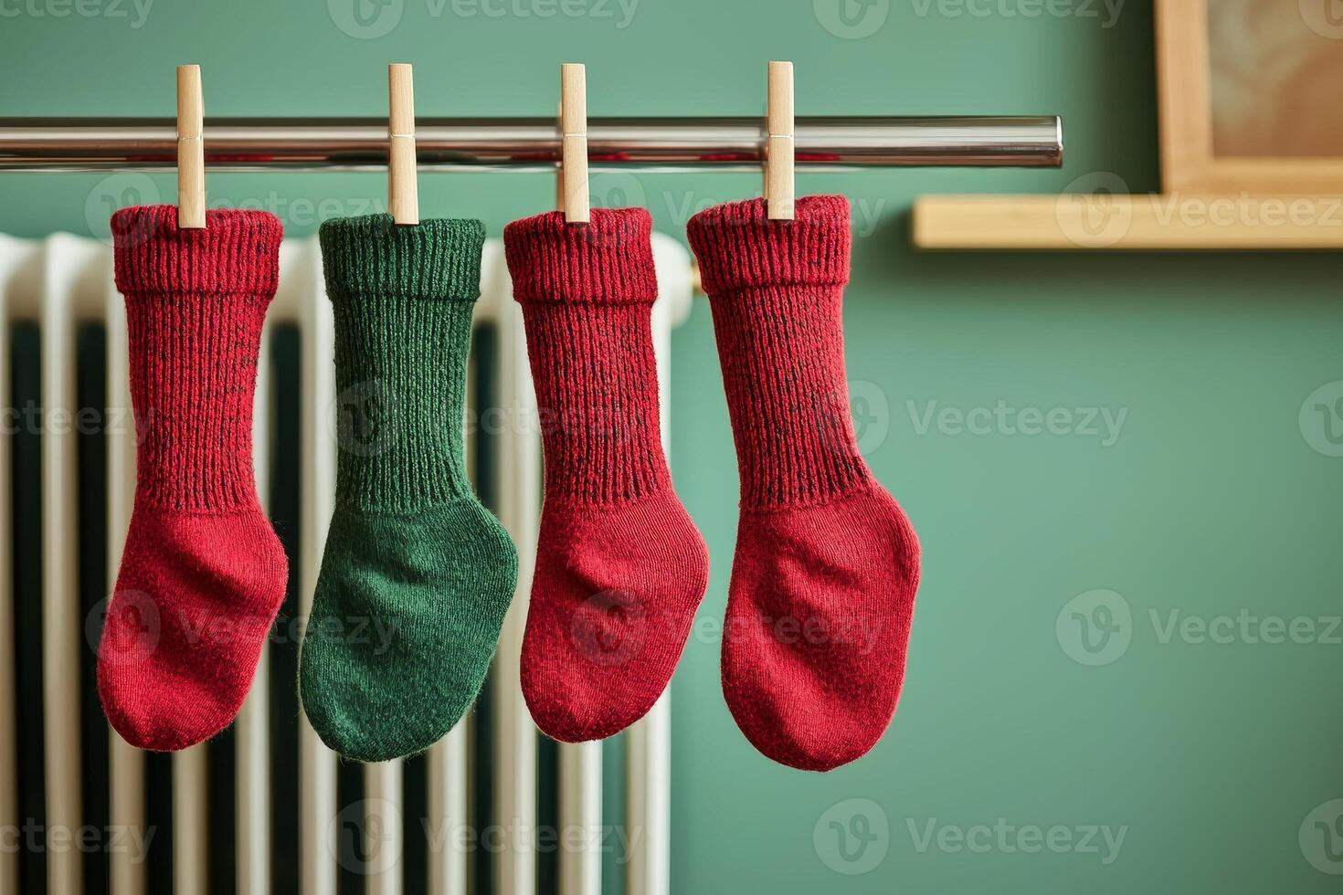 Four colorful knitted socks hanging on a clothesline against a soft green wall. photo