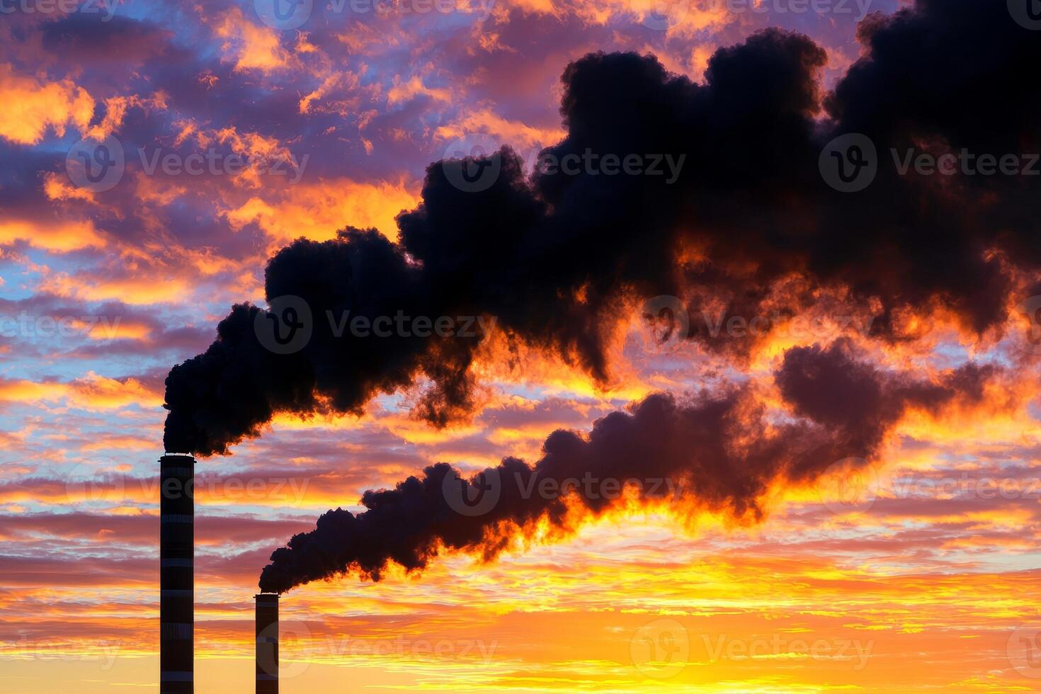 Smoke billowing from industrial chimneys against a dramatic sunset sky. photo