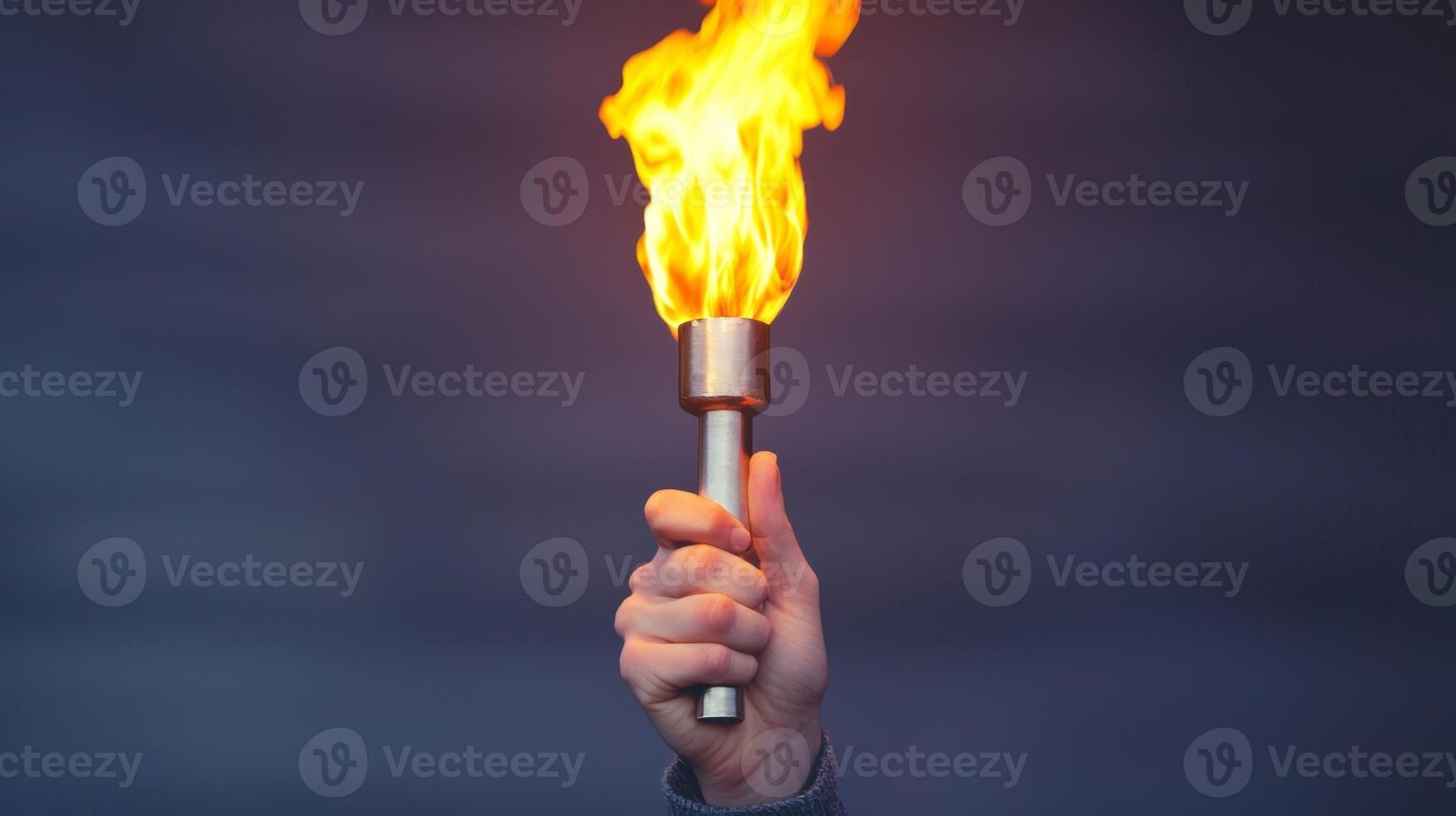 Hand holding a torch with a bright flame against a blurred background. photo