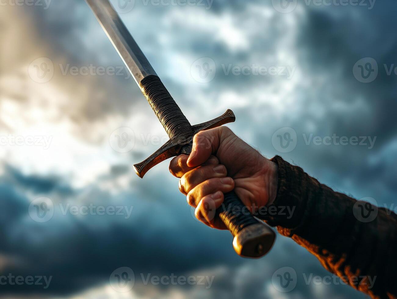 A hand grasping a sword against a dramatic cloudy sky. photo