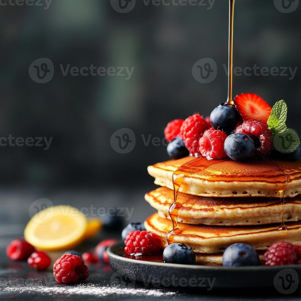 Stack of pancakes topped with berries and syrup on a dark background. photo