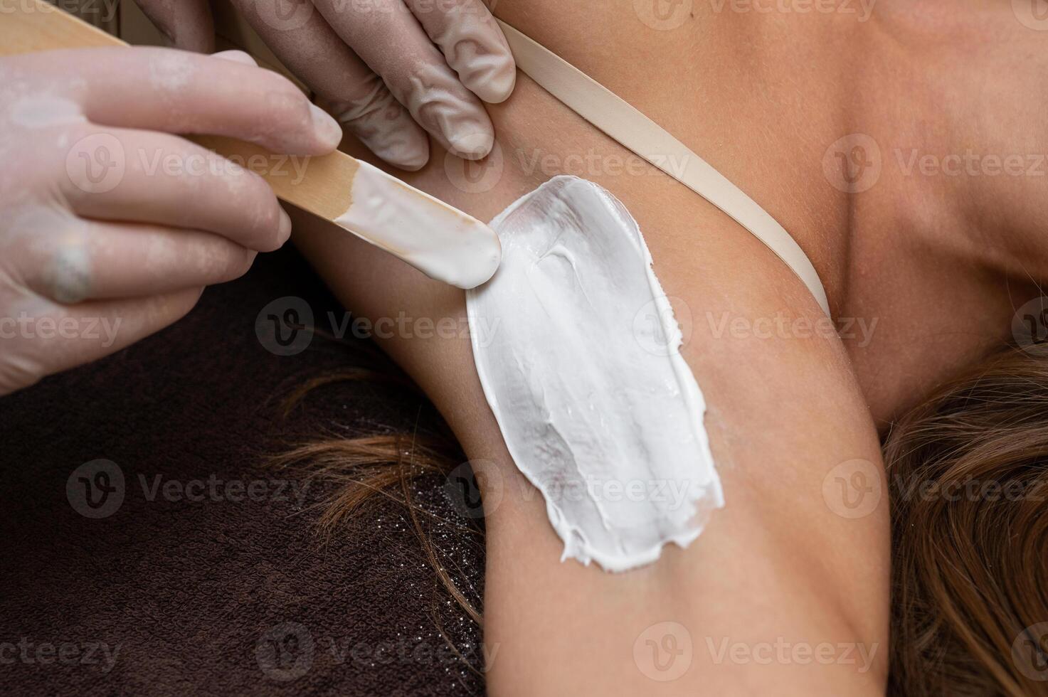 Cosmetologist in beauty clinic performs a epilation procedure photo