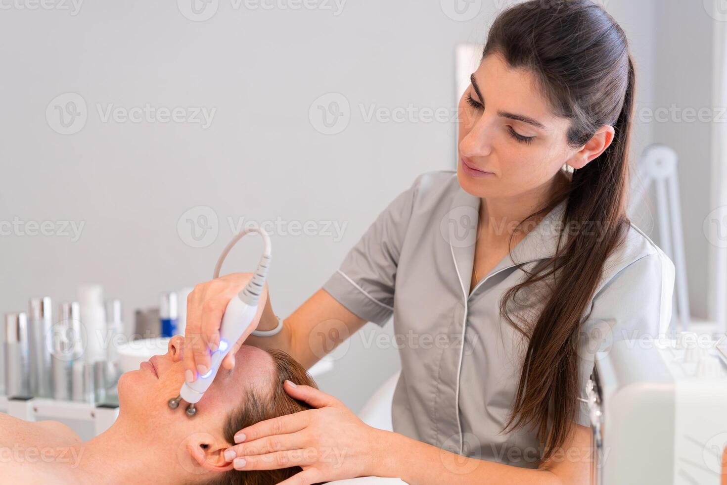 Woman receiving facial ultrasonic skincare treatment in clinic photo