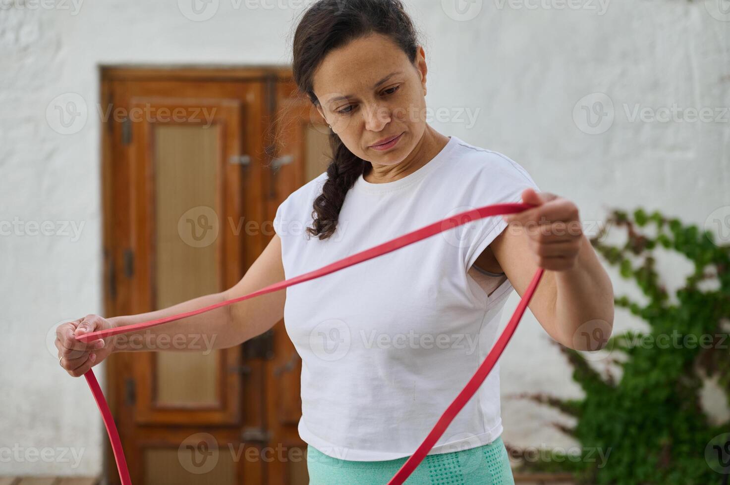 Woman in white t-shirt stretching with resistance band outdoors for fitness exercise and healthy lifestyle photo