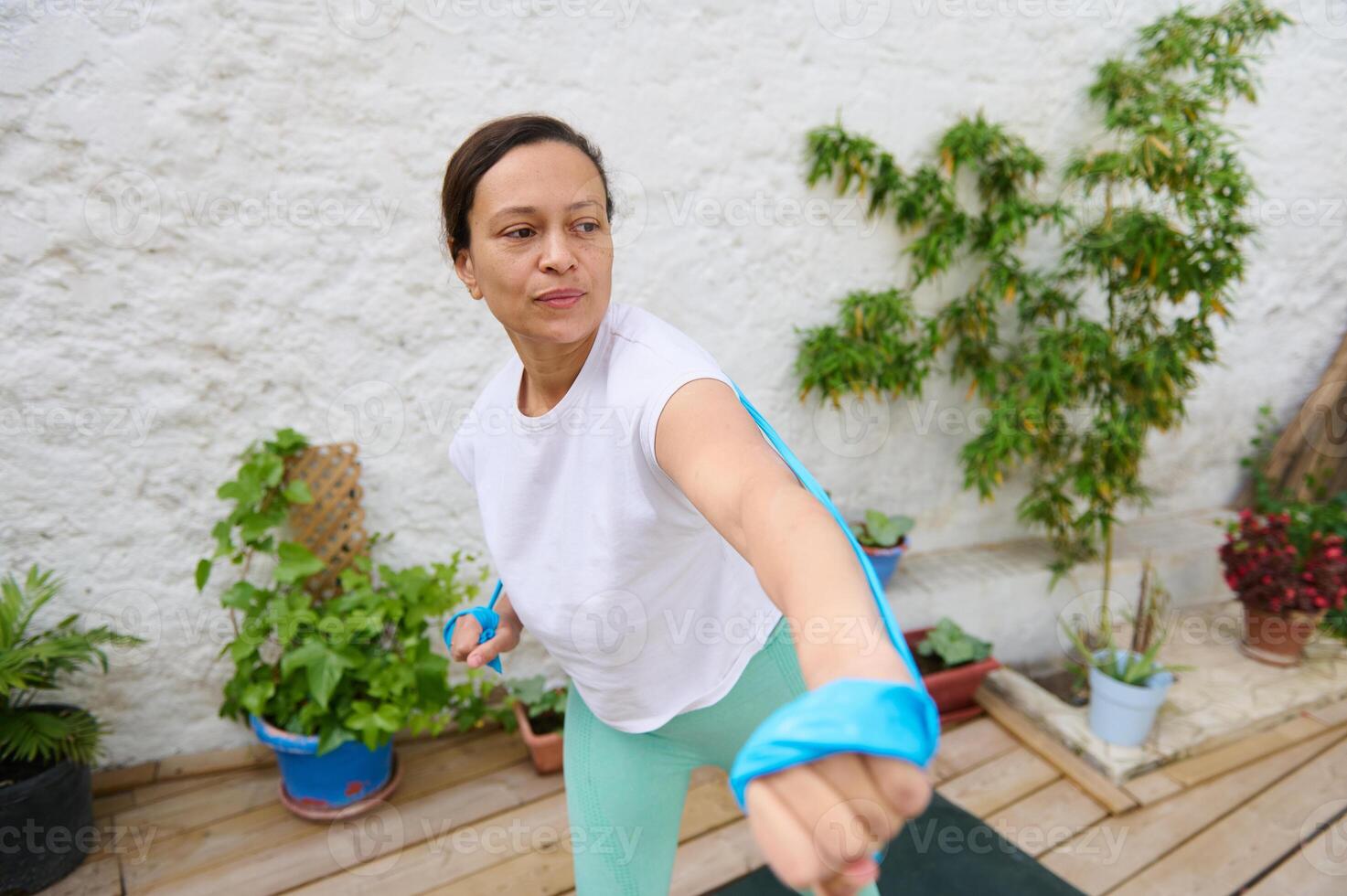 Woman exercising with resistance band in garden showing dedication and fitness lifestyle outdoors photo