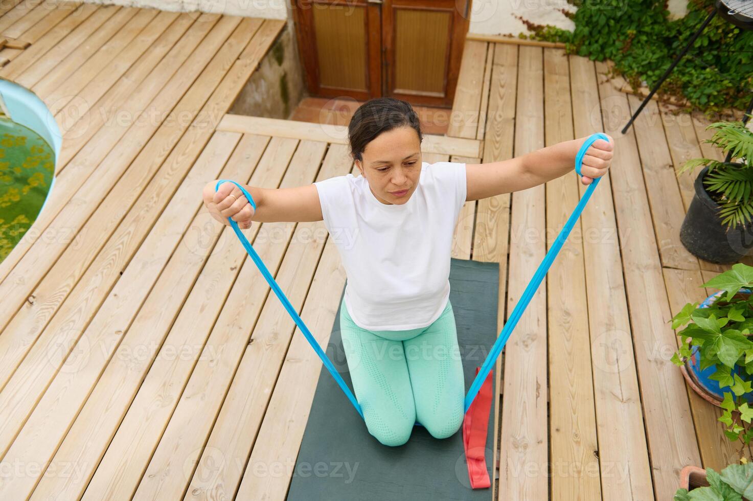 Woman exercising with resistance band on wooden deck for healthy outdoor workout and fitness routine photo