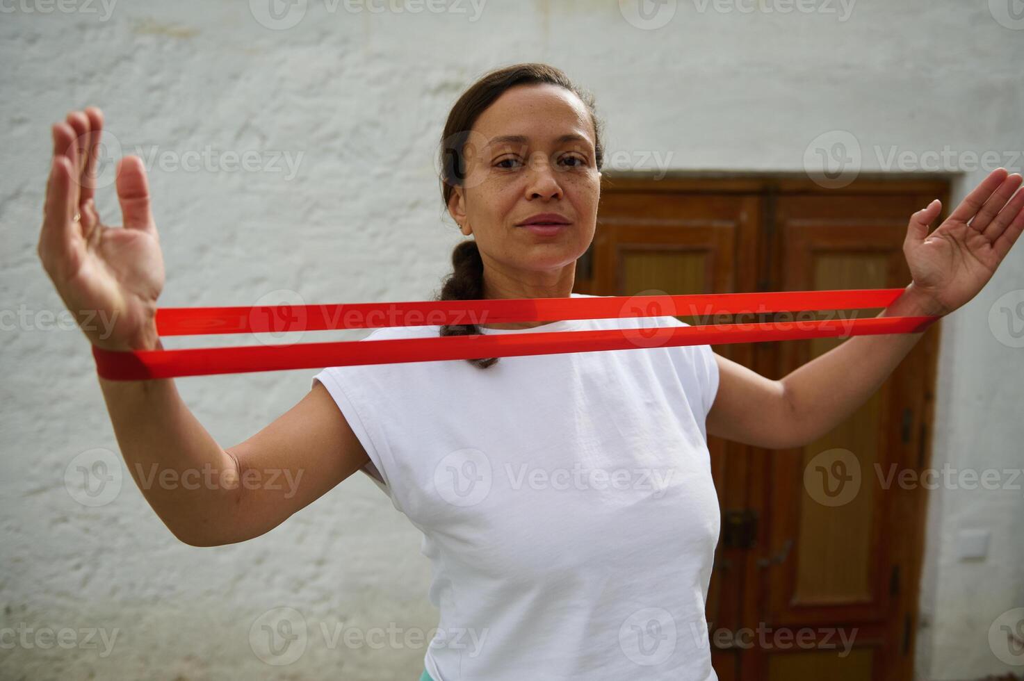 Confident woman practicing resistance band exercises outdoors for fitness and strength training in a relaxed setting photo