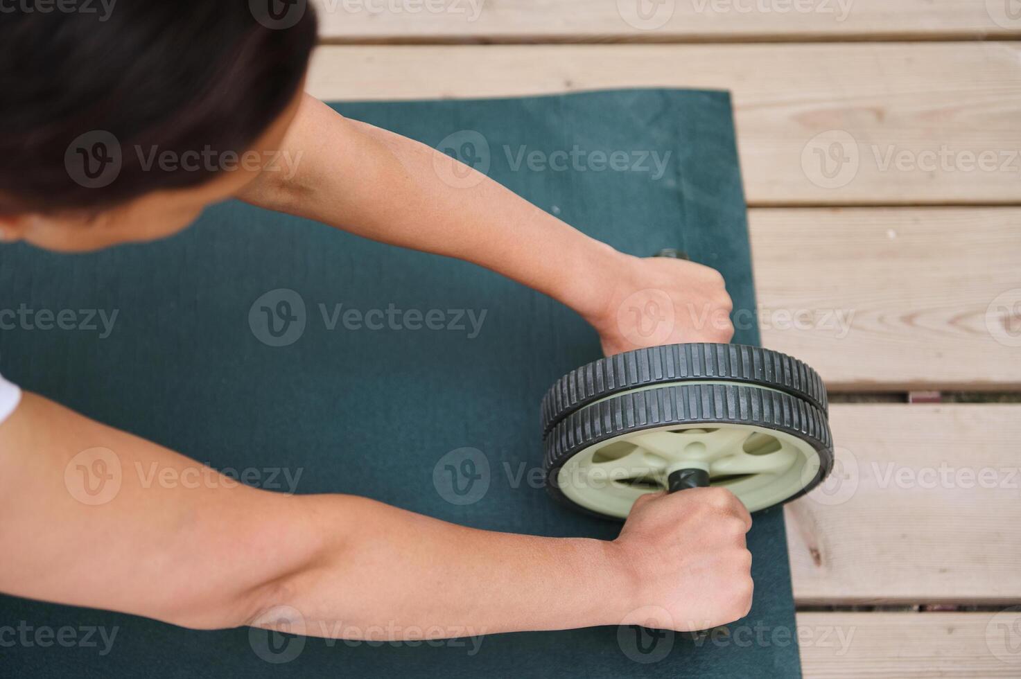 Person exercising with abdominal roller on yoga mat outdoors for core strength and fitness routine photo