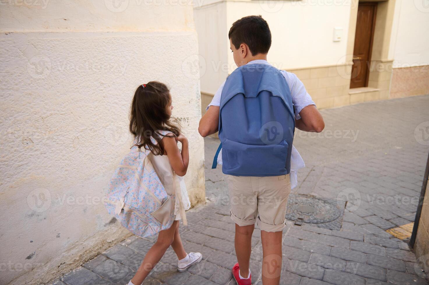 Children walking to school with backpacks on a sunny day photo