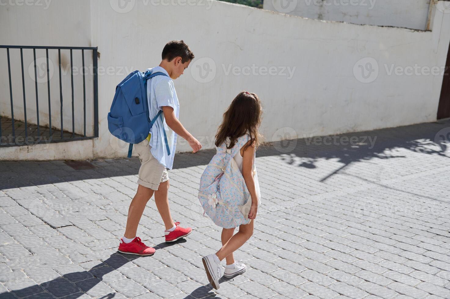 Children walking to school with backpacks on a sunny day photo
