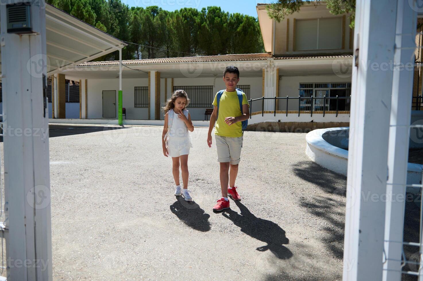 Two children walking outside school on a sunny day photo