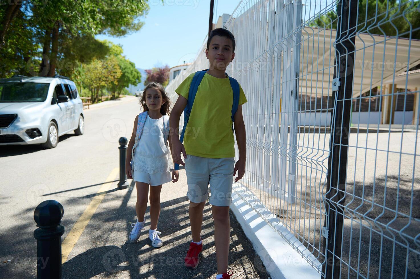 Children walking to school on a sunny morning with backpacks photo