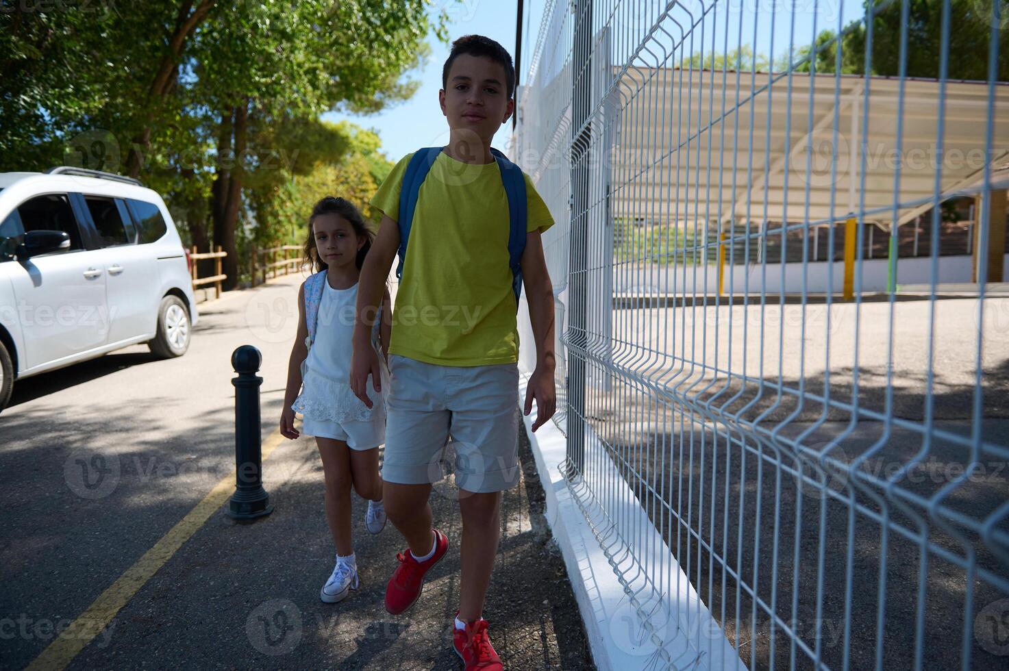 Children walking to school on a sunny day with backpacks photo