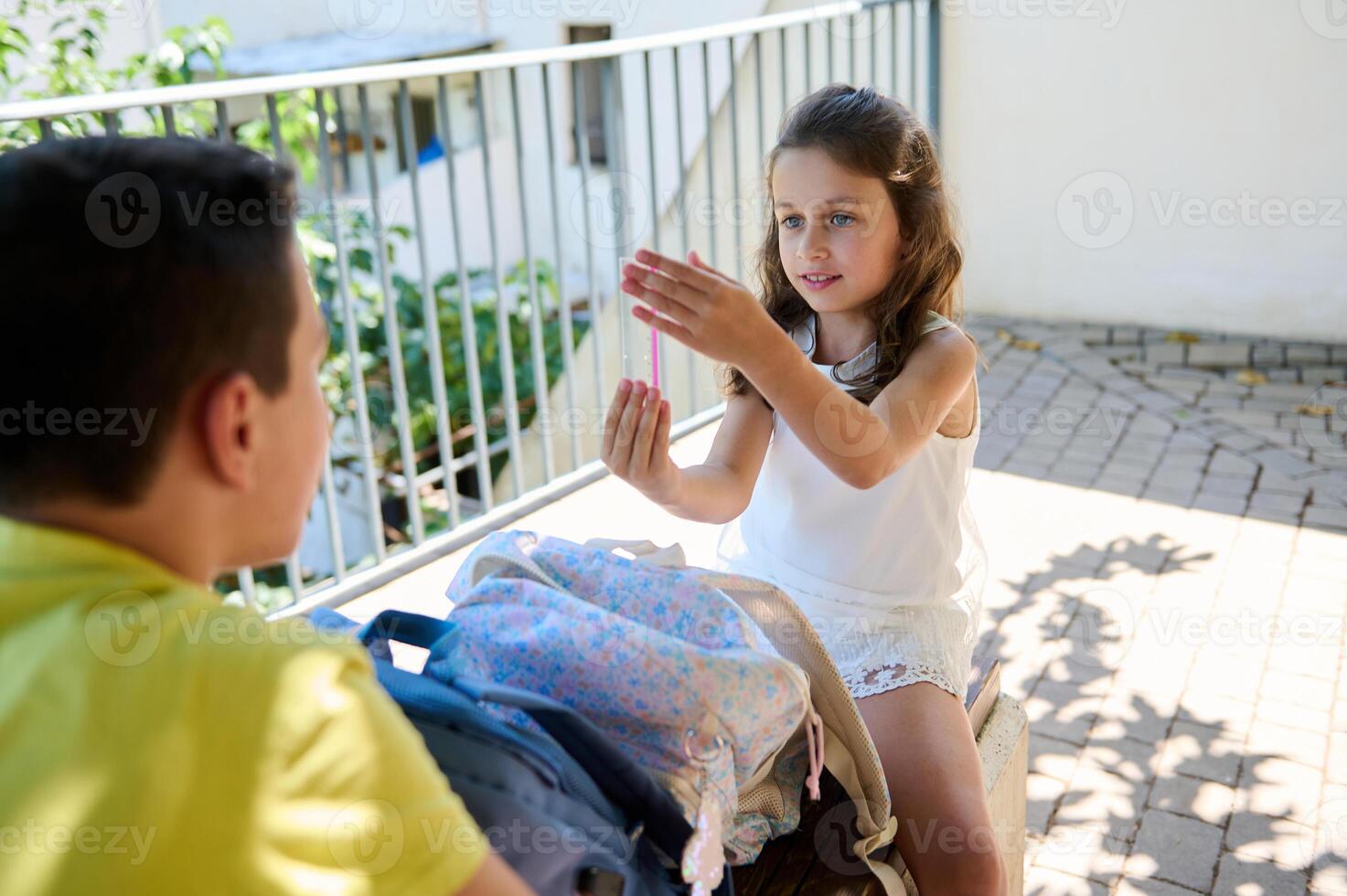 Young girl showing handmade craft to boy outdoors photo