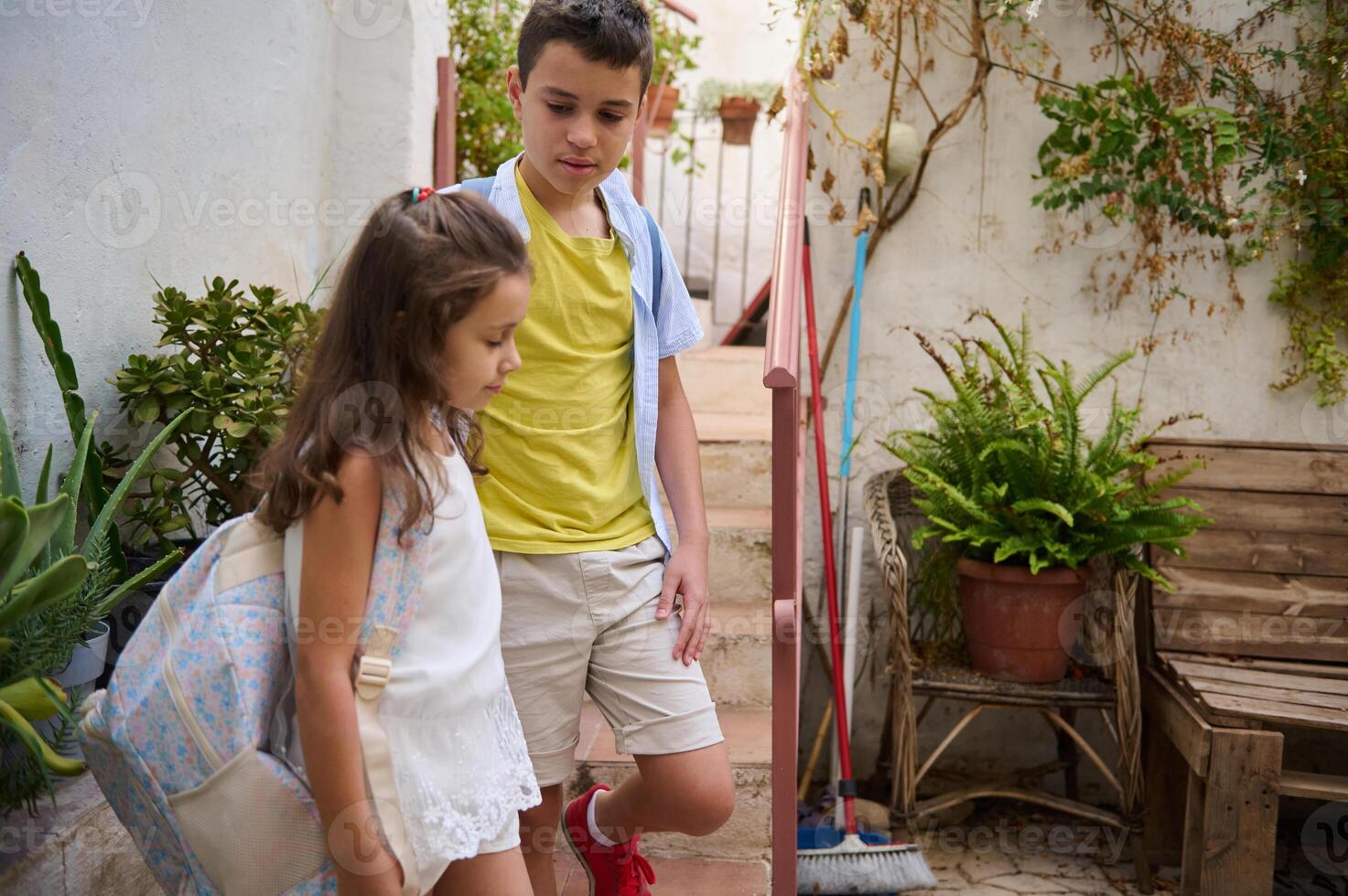 Children with backpacks walking down outdoor stairs photo