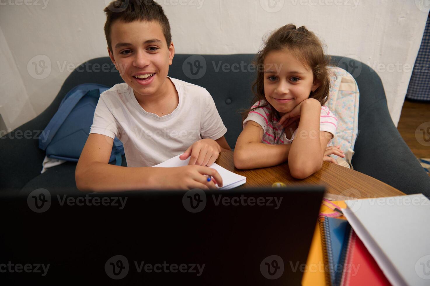 Smiling siblings enjoying online learning at home together photo