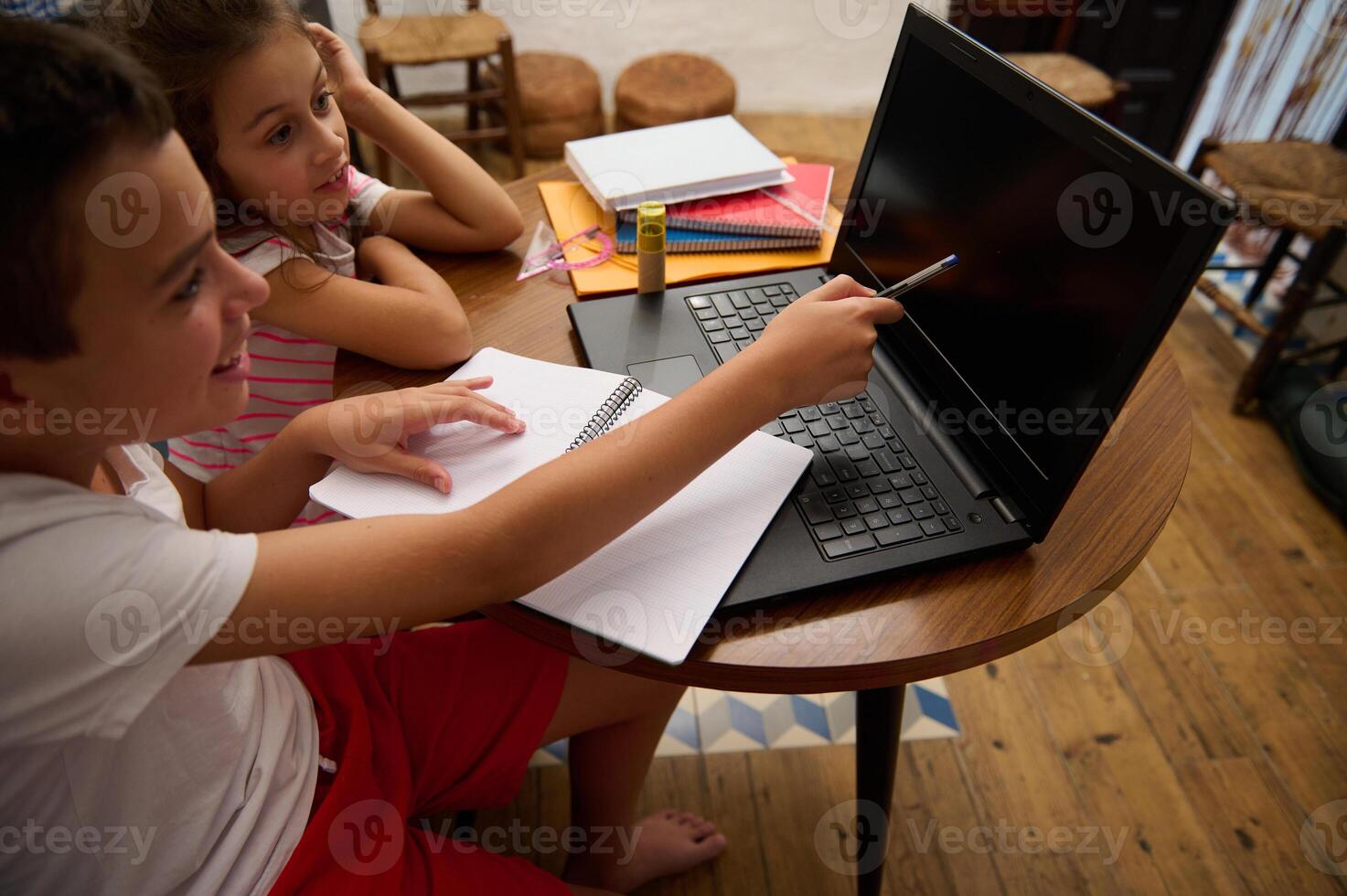 Children learning together with laptop and notebook at home photo