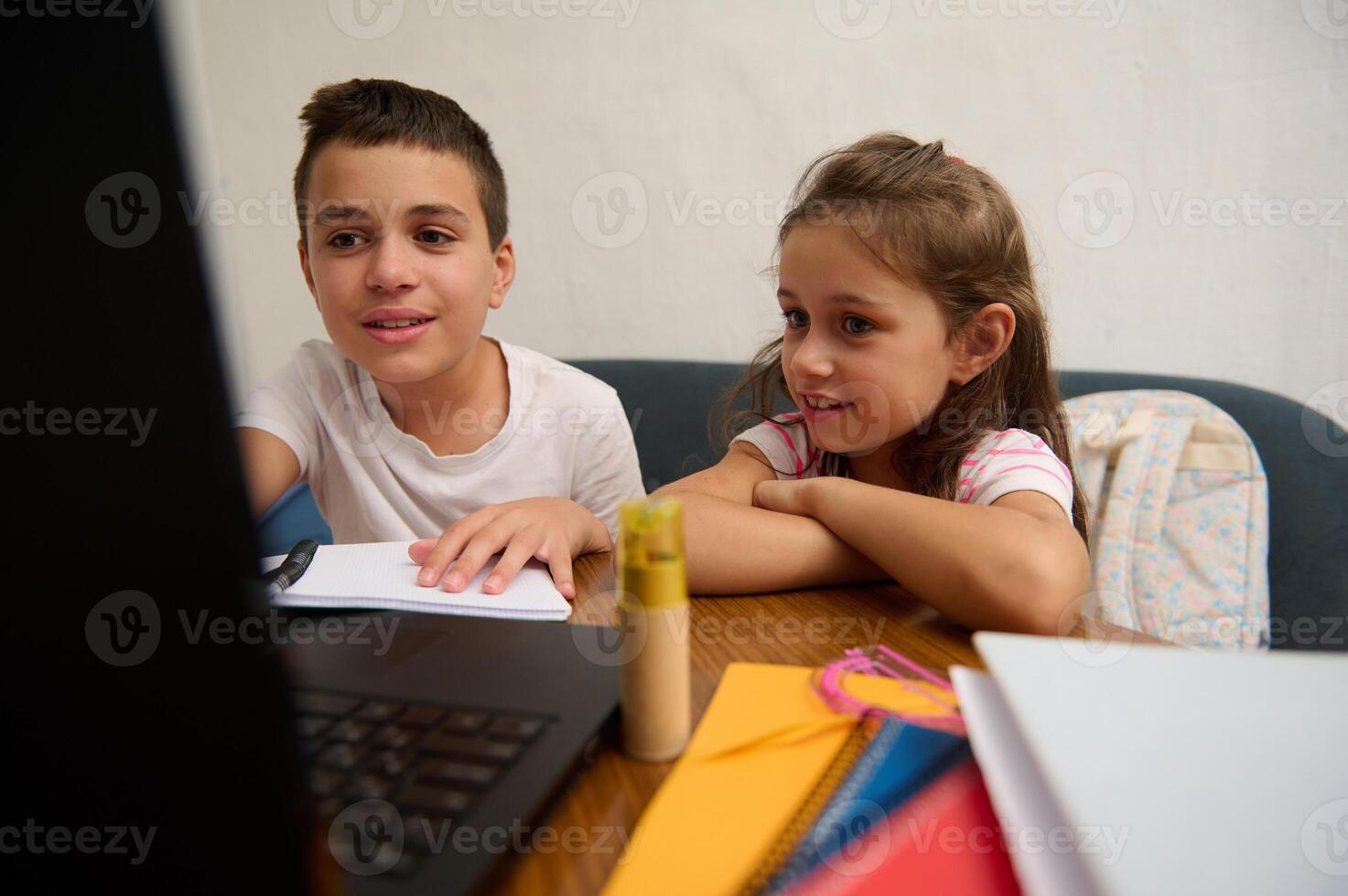 Children learning together at home using a laptop and books photo