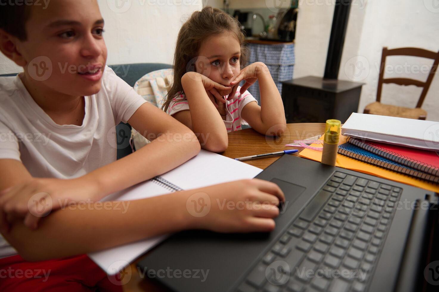 Children learning at home with laptop and notebooks photo