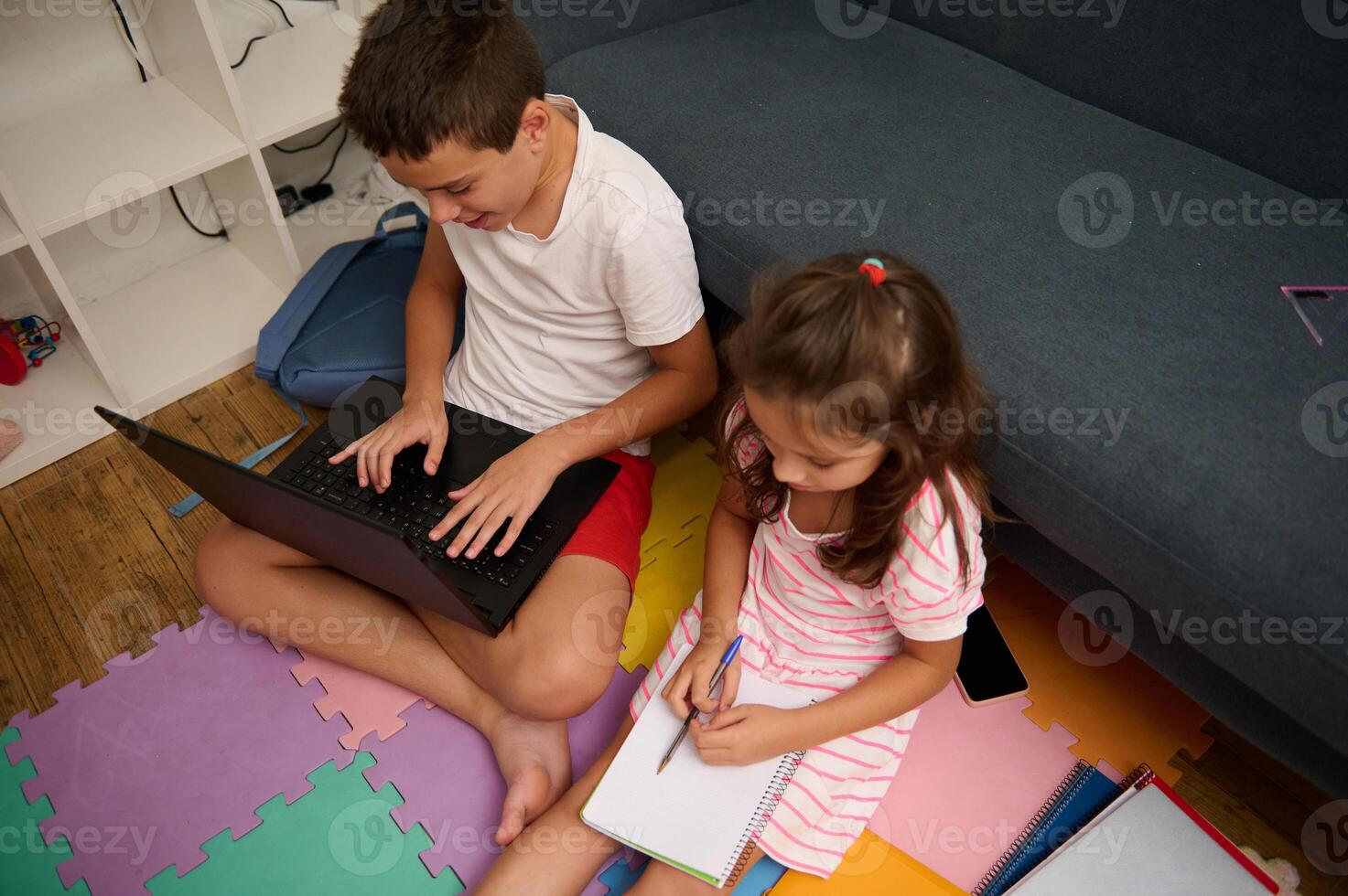 Children learning together at home on laptop and notebook photo