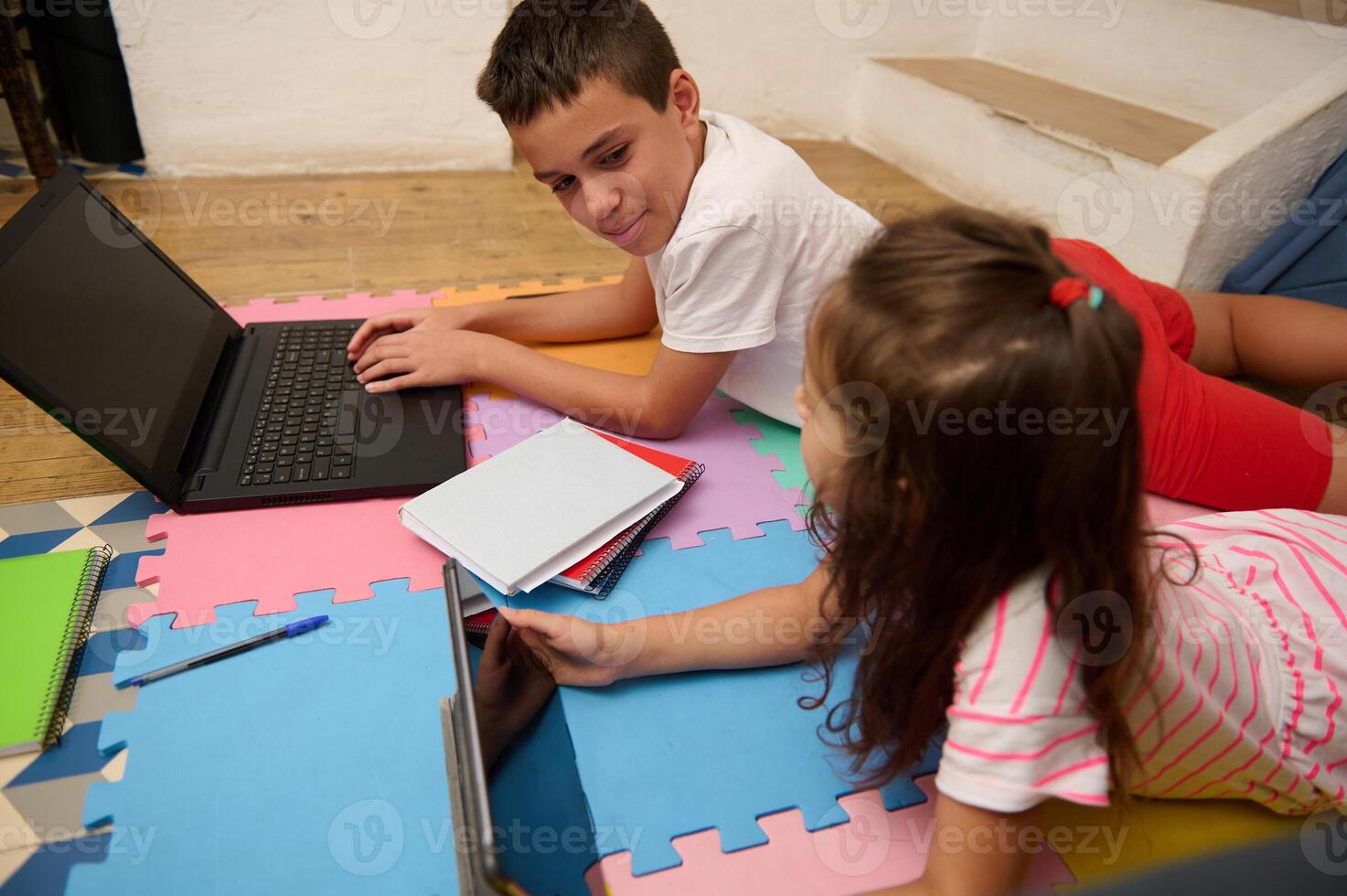Kids learning together on laptops in home setting photo