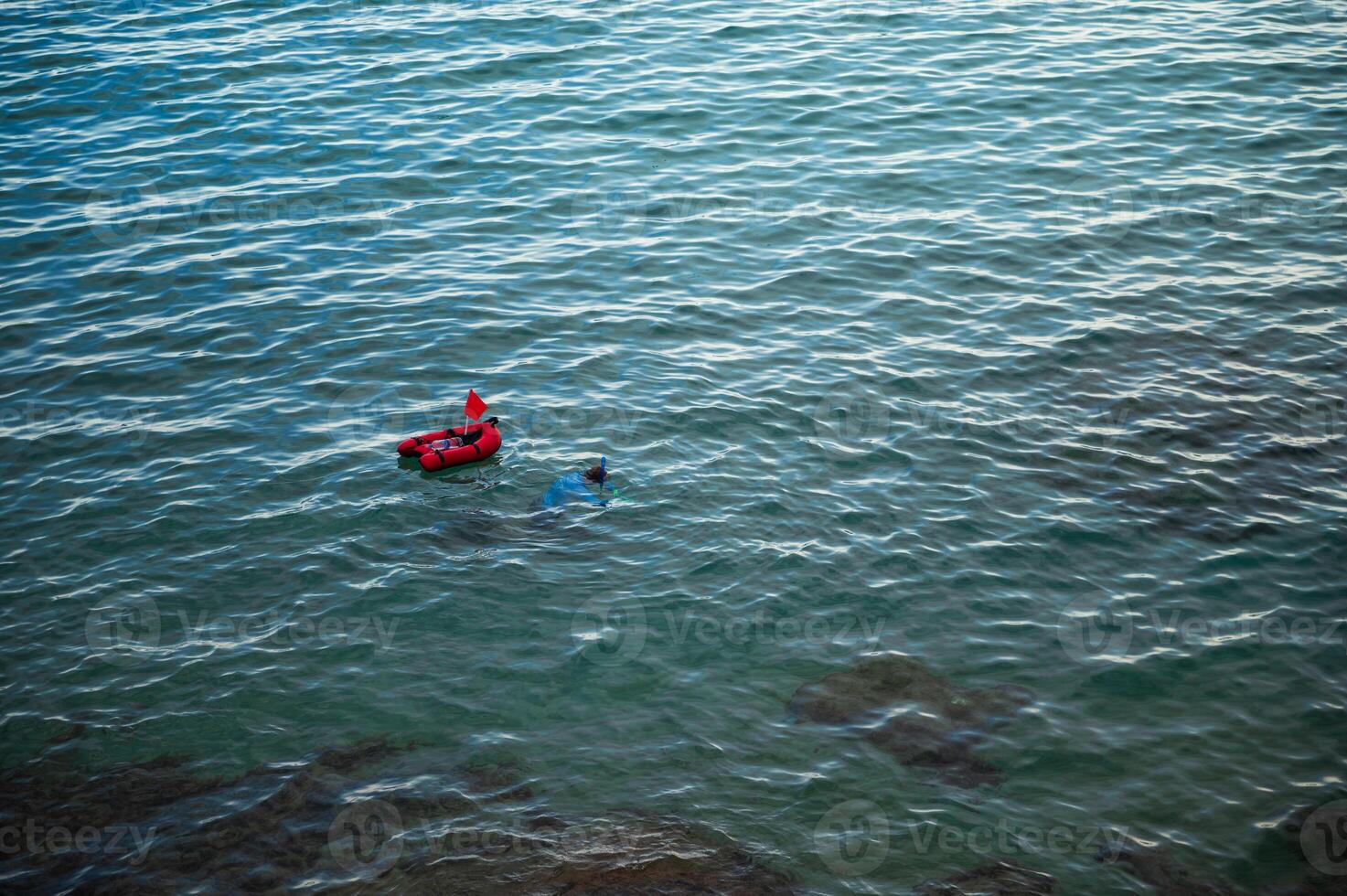 Snorkeler exploring calm ocean waters with buoy and flag photo