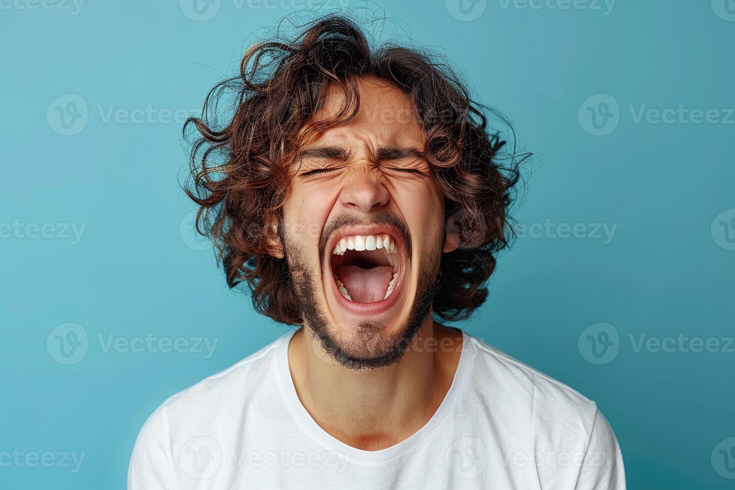 A man with curly hair is screaming with his mouth wide open. photo