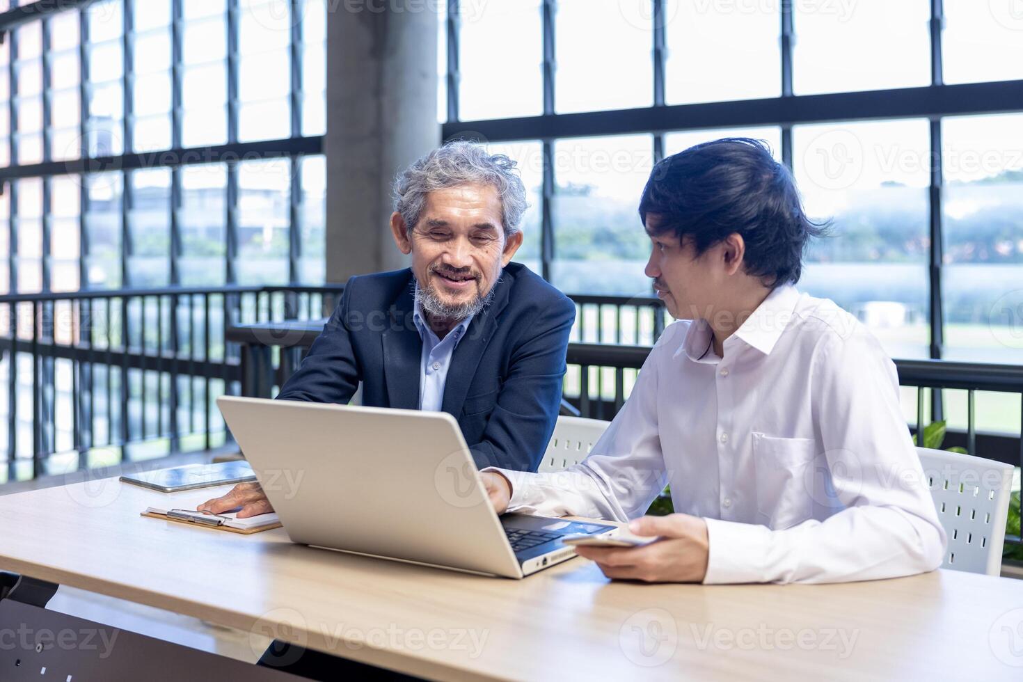 Asian senior professor is giving his advice to the college student on the research thesis while sitting in the university faculty for education, academic and business photo