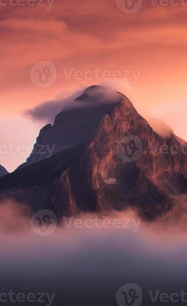 A mountain is covered in clouds at sunset photo