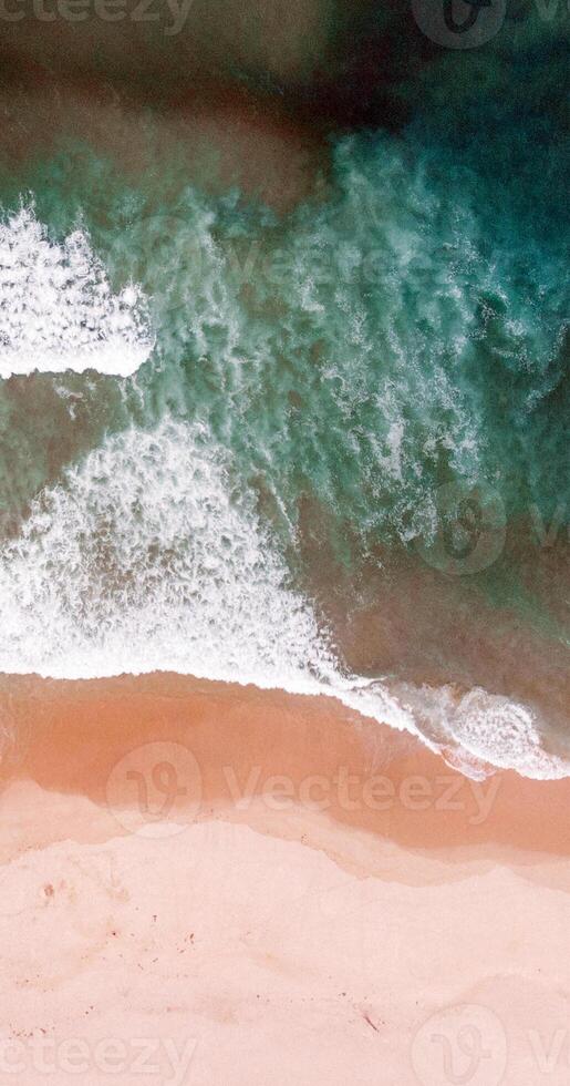 An aerial view of a beach with waves and a person on a surfboard photo