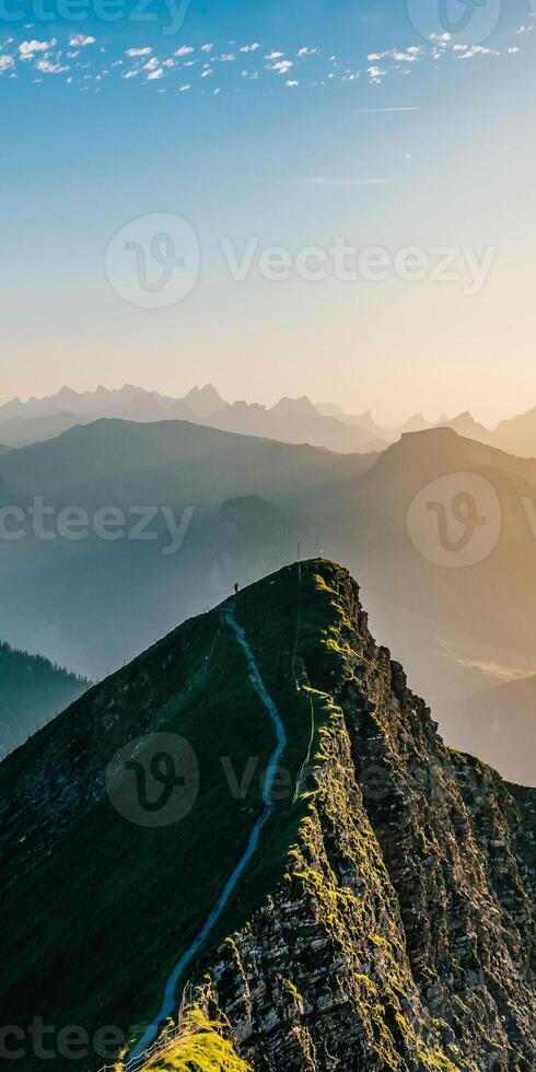 A mountain top with a path leading down to the valley photo