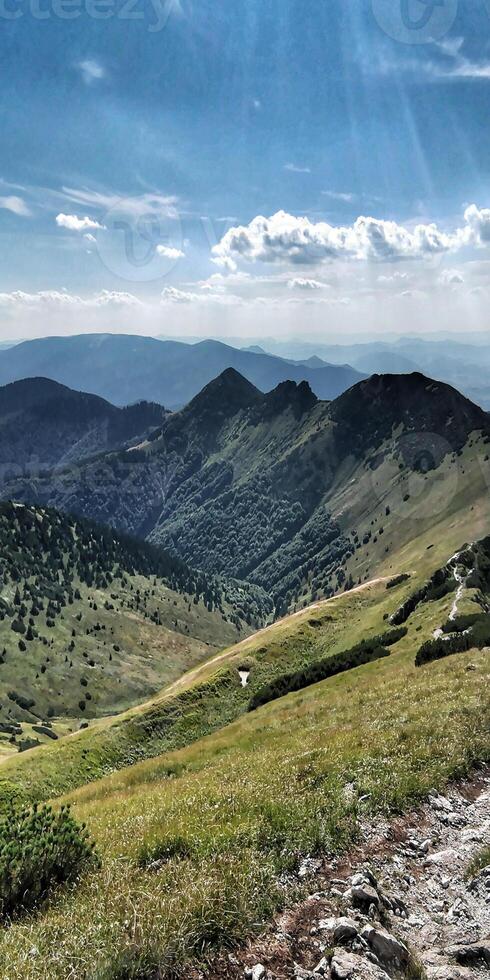 A man is walking on a trail in the mountains photo