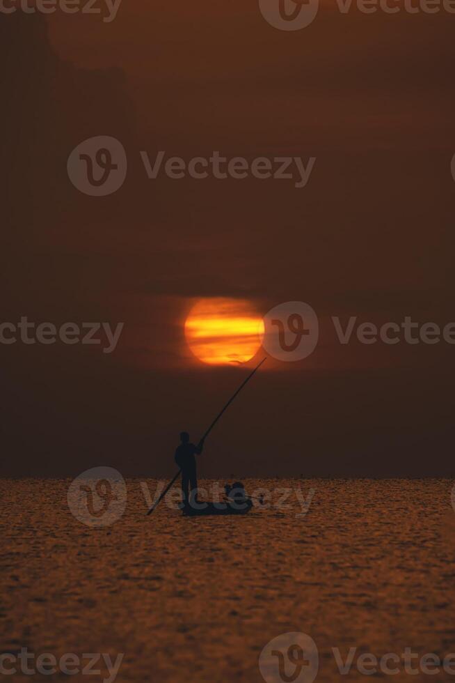 Silhouette fisherman with sunset sky on the lake photo