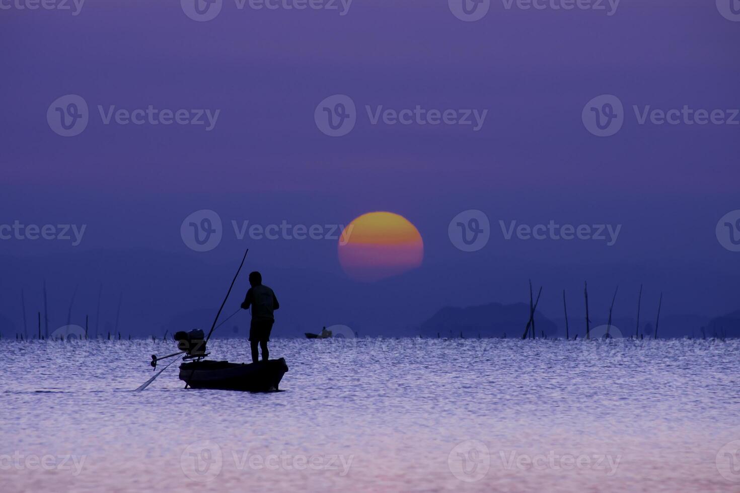 Minimal silhouette fishermans on the lake with twilight sky. photo