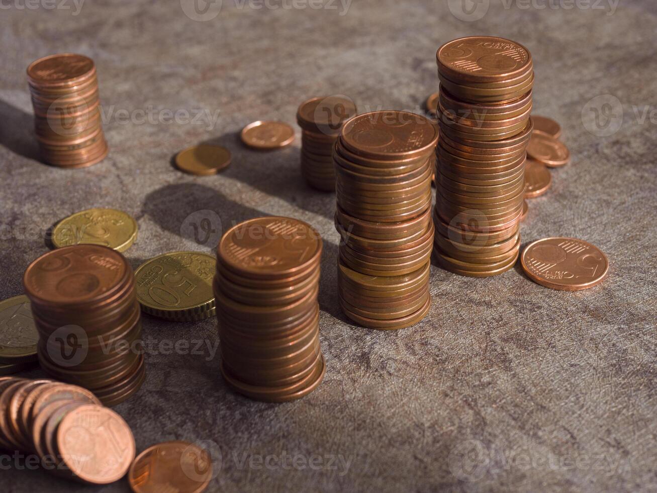 Euro money cents arranged in columns create striking display, with small coins scattered around. glimmer of metal reflects light, emphasizing value. A detailed view of money cents and their texture. photo