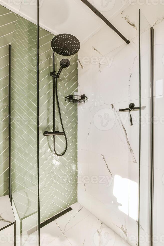 A bathroom with a green tile wall and a glass shower photo