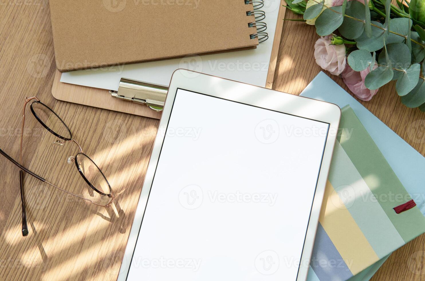 A cozy workspace setup featuring a tablet, stationery, and fresh flowers in soft natural light for inspiration and creativity photo
