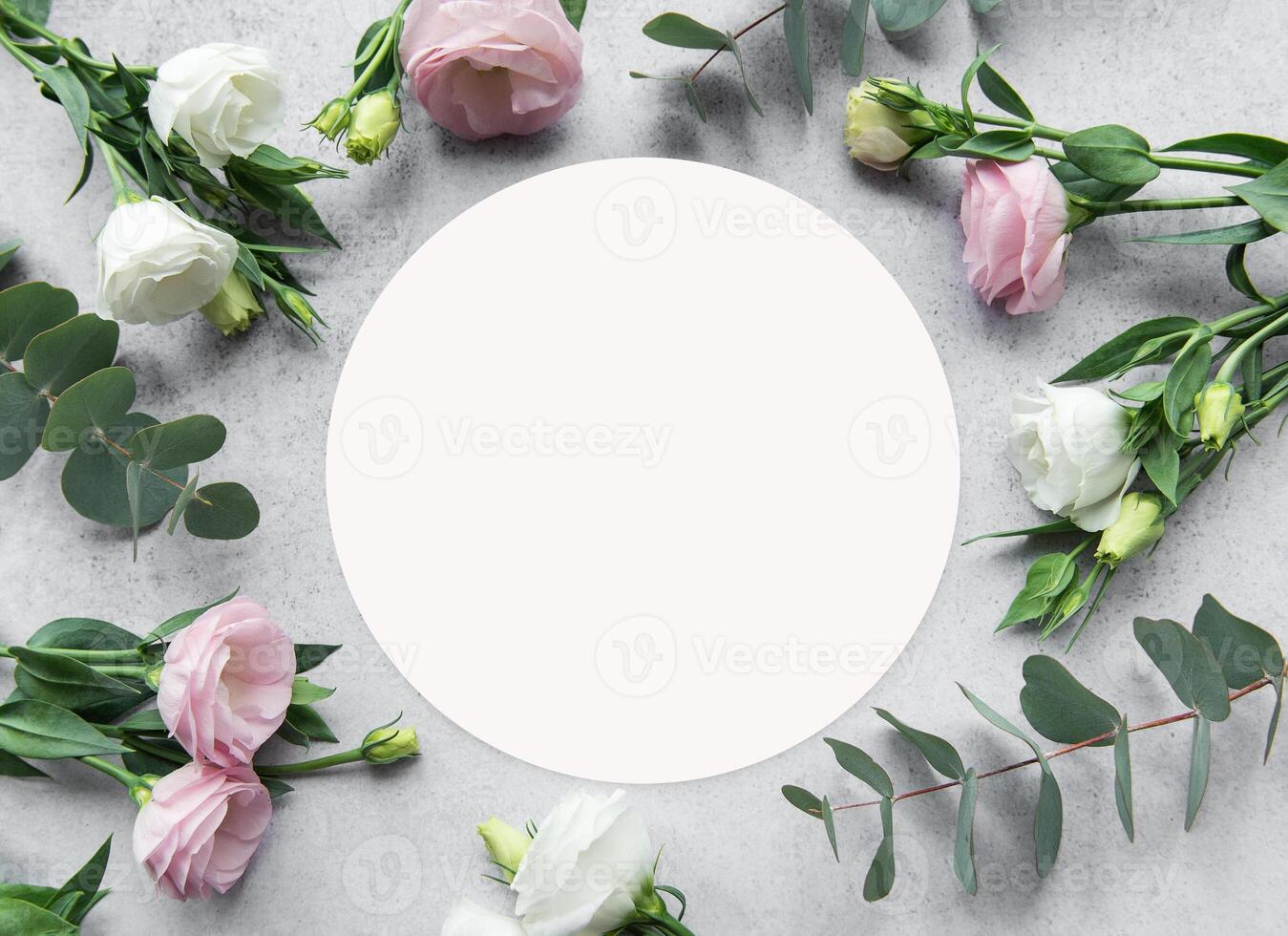 Delicate arrangement of pink and white flowers surrounding a blank circle on a textured surface photo
