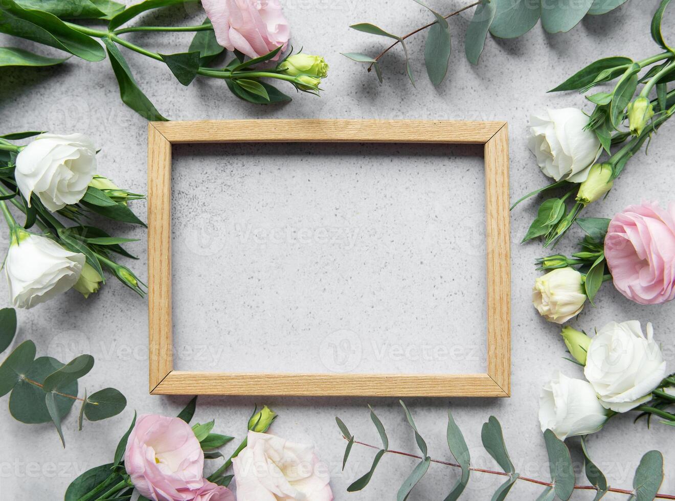 Delicate flowers arranged around an empty wooden frame on a textured surface photo