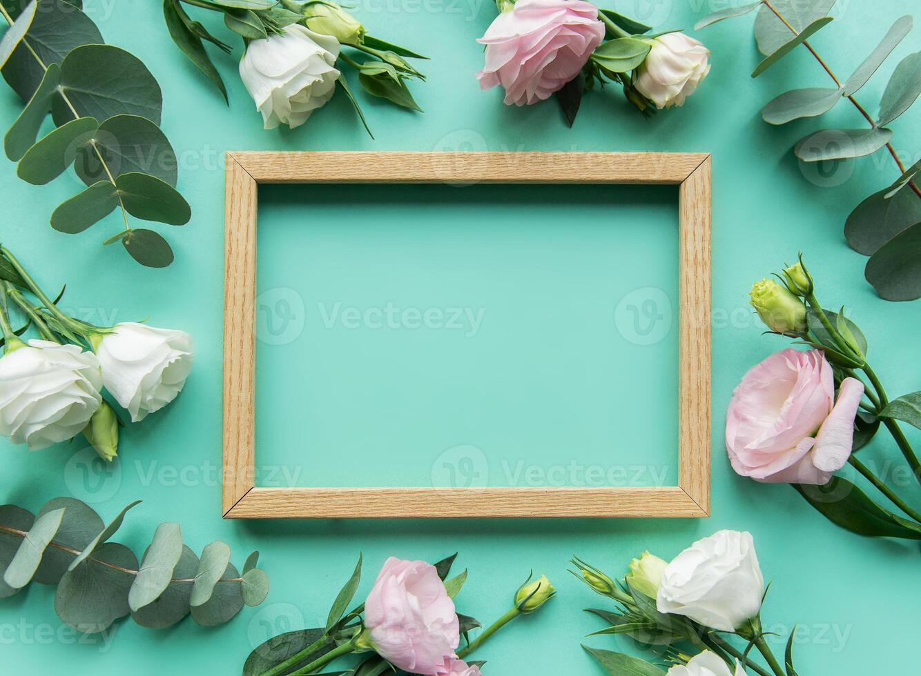 A wooden frame surrounded by white and pink roses on a mint green background for a decorative or artistic display photo