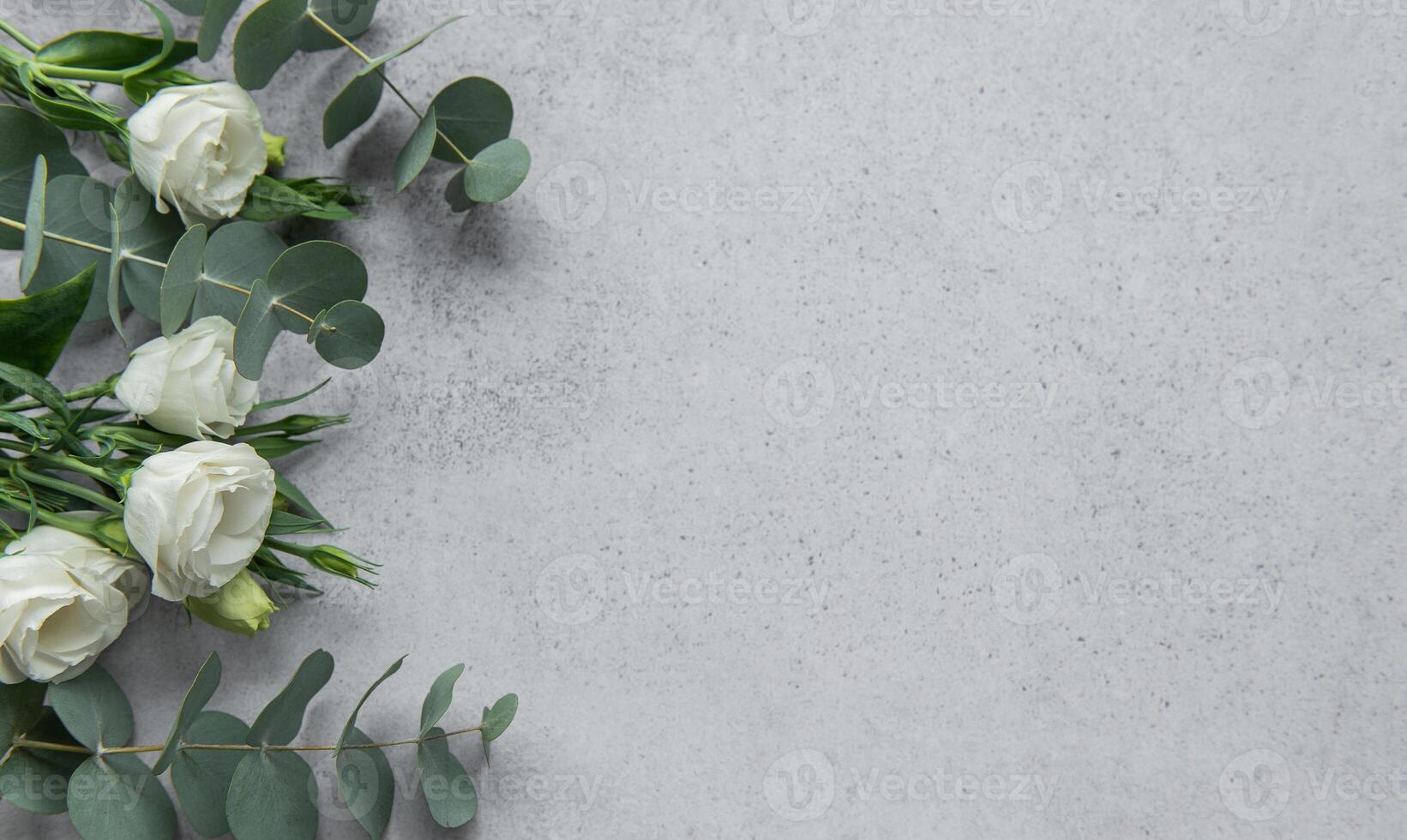 Delicate arrangement of mixed flowers and eucalyptus leaves on a light grey surface photo