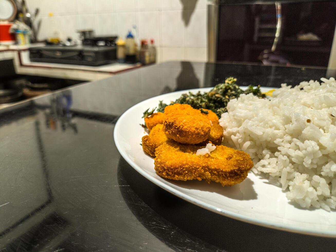 A delicious plate featuring golden nuggets, fluffy scrambled eggs, and crispy fried spinach, served with white rice. Perfect for a balanced meal with a variety of textures and flavors photo