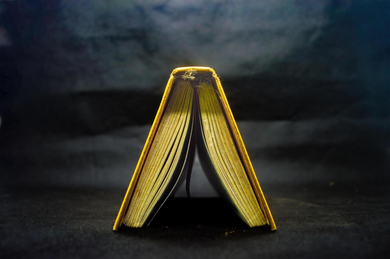 Open Quran book with golden edges on dark background, showcasing intricate Arabic script, symbolizing Islamic faith and spirituality photo