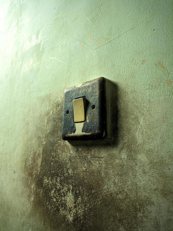 Close up of an old, weathered electrical switch on a wall with peeling paint, showcasing vintage and rustic textures. Ideal for backgrounds, design projects, and adding a retro touch to your work photo