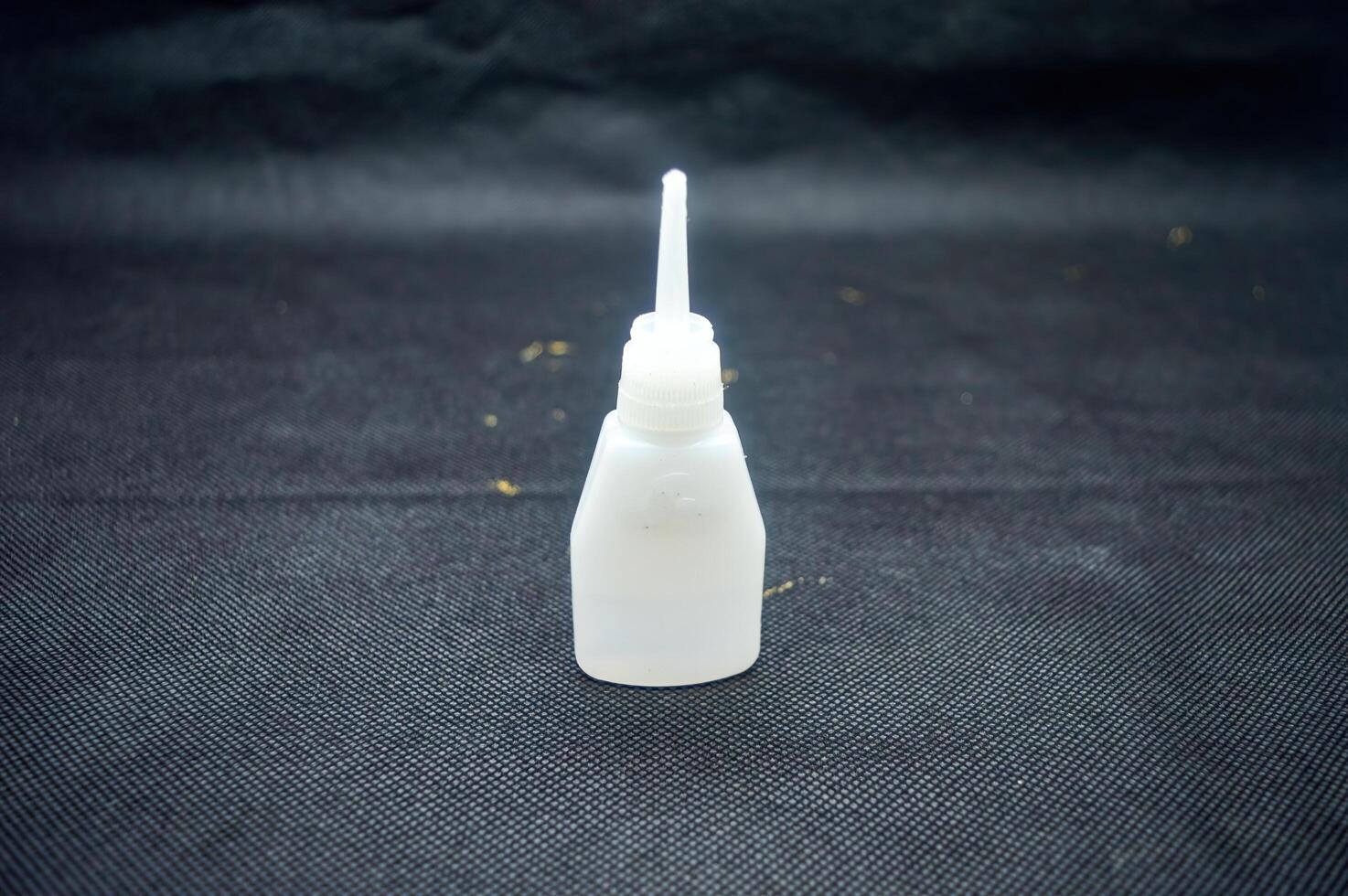 Close up of Cyanoacrylate Ethyl adhesive bottle on dark textured surface, essential for quick repairs photo