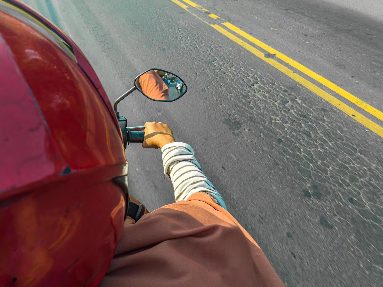 Close up of a motorcyclist on an open road, focusing on the helmet, arm, and side mirror, capturing the essence of a thrilling ride photo