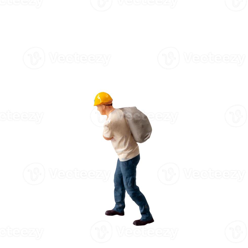 Miniature construction worker carrying a heavy sack on his back isolate on white background with clipping path photo