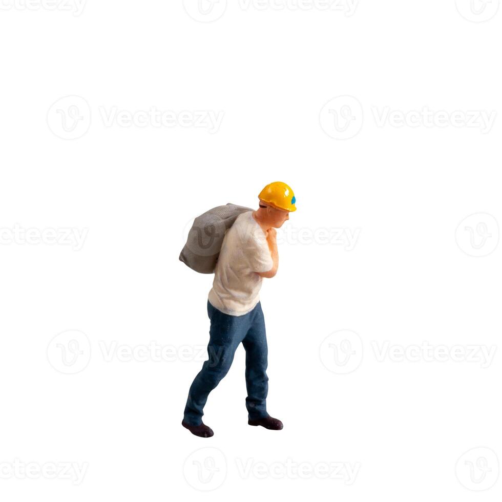 Miniature construction worker carrying a heavy sack on his back isolate on white background with clipping path photo