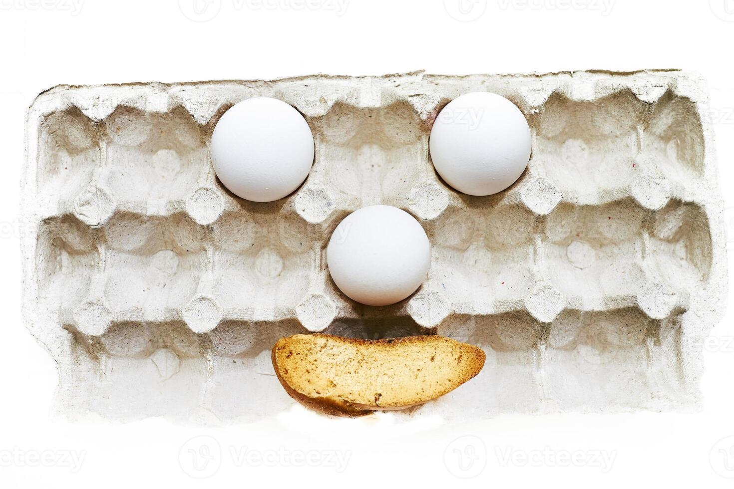 Comic face made of three eggs and sausages in cardboard packaging photo